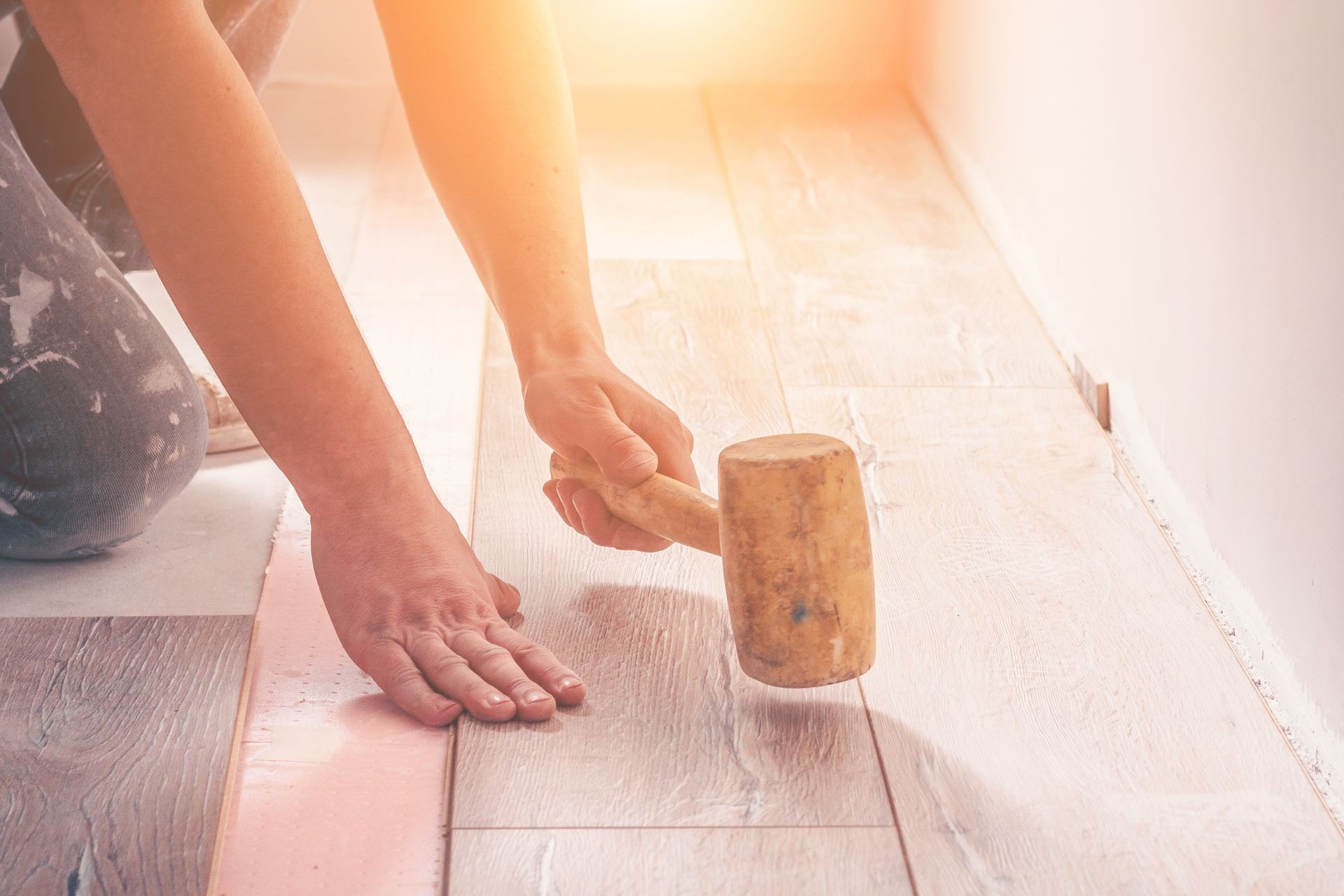 The worker's hand with a hammer mounts the floorboard into place, professional laying of the flooring, laminate